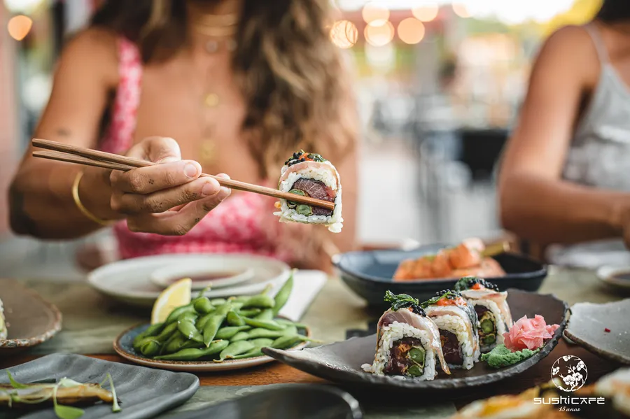 SushiCafé cover photo featuring a woman enjoying sushi, capturing the dining experience and delicious offerings.